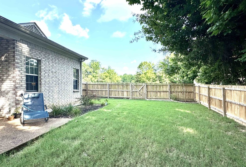 Expansive backyard featuring a manicured lawn, full privacy fencing, and mature perimeter trees