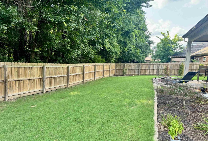 Expansive backyard featuring a lush lawn, privacy fencing, and mature perimeter trees