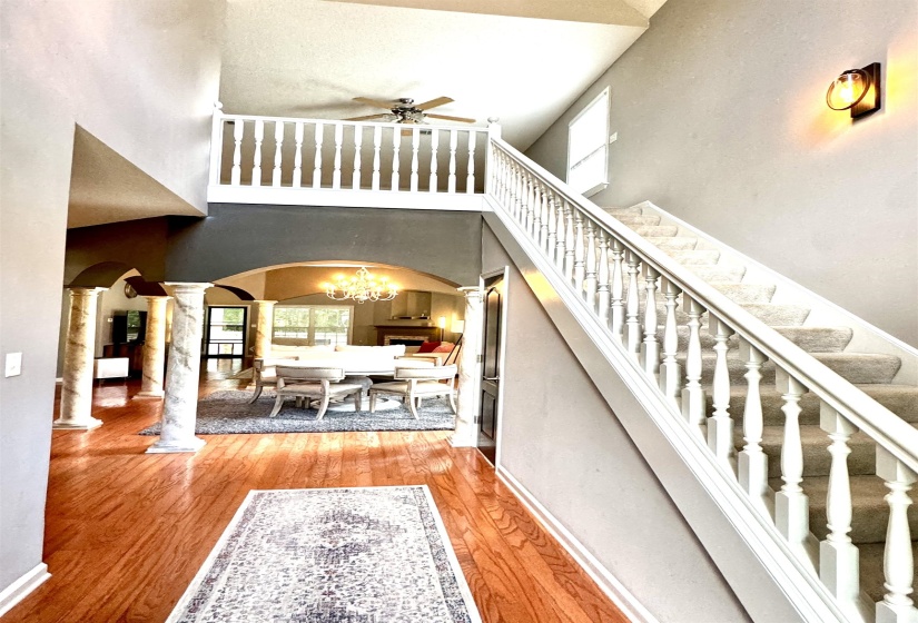 Grand entryway featuring a staircase with white balusters, wood-finish flooring, and a second-story landing with an open railing