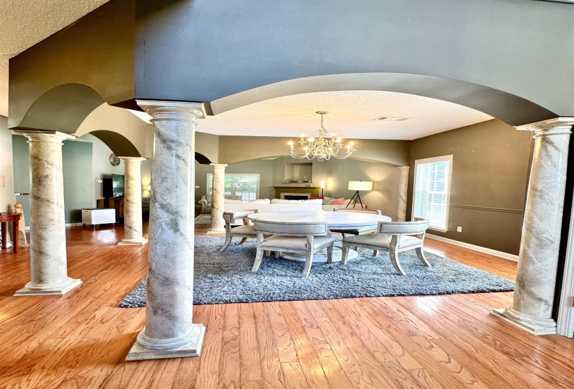 Architectural columns and arched doorways define the space, featuring wood-finish flooring