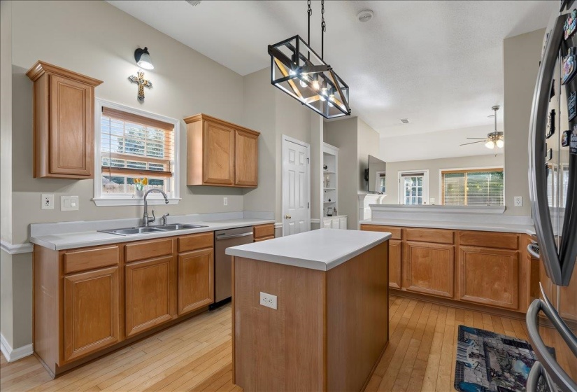Kitchen featuring wood-finish cabinetry, light-toned countertops, a stainless steel sink, and wood-finish flooring