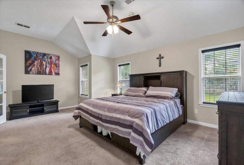 Bedroom featuring vaulted ceilings, carpet flooring, a ceiling fan with integrated lighting, and multiple windows with blinds