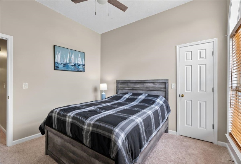 Carpeted interior room featuring neutral wall tones, a vaulted ceiling, and a ceiling fan