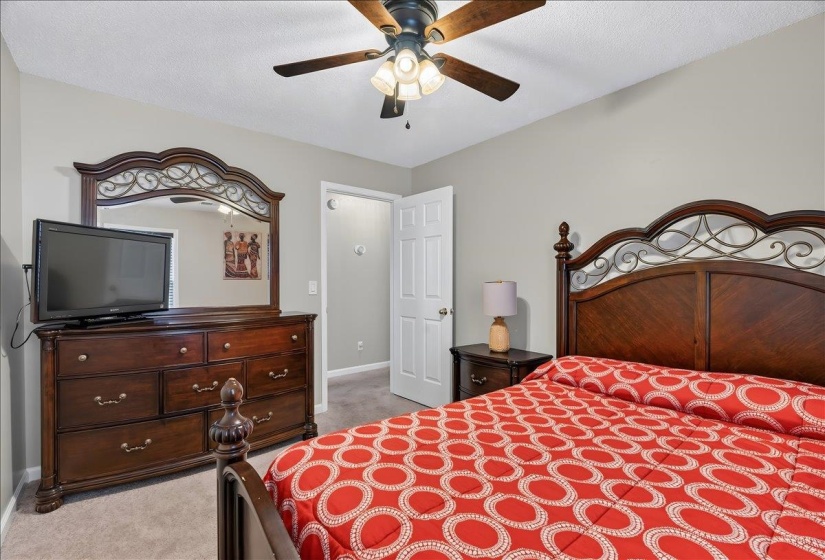 Carpeted room featuring light gray walls, a ceiling fan with integrated lighting, and a white interior door