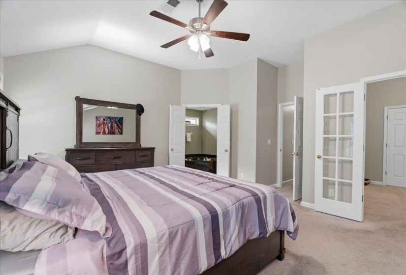 Vaulted ceiling room featuring a ceiling fan with light fixture, neutral wall paint, and carpet flooring