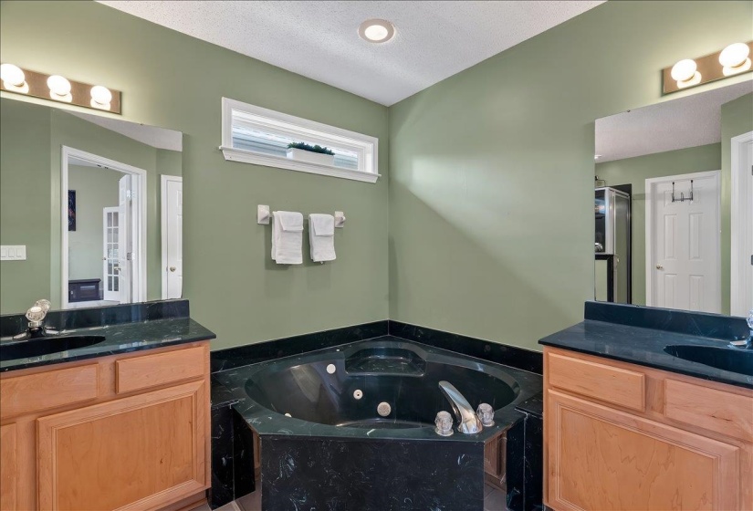 Corner jetted tub with dark stone surround