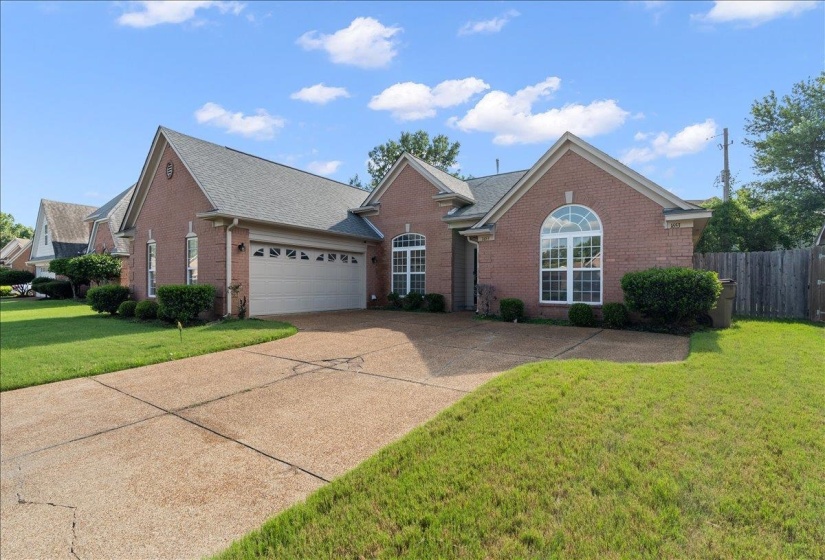 Brick exterior featuring a two-car garage, arched window, and gabled roofline