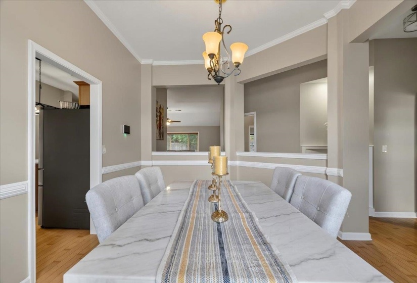 Formal dining space featuring crown molding, chair rail molding, wood-finish flooring, and an ornate chandelier