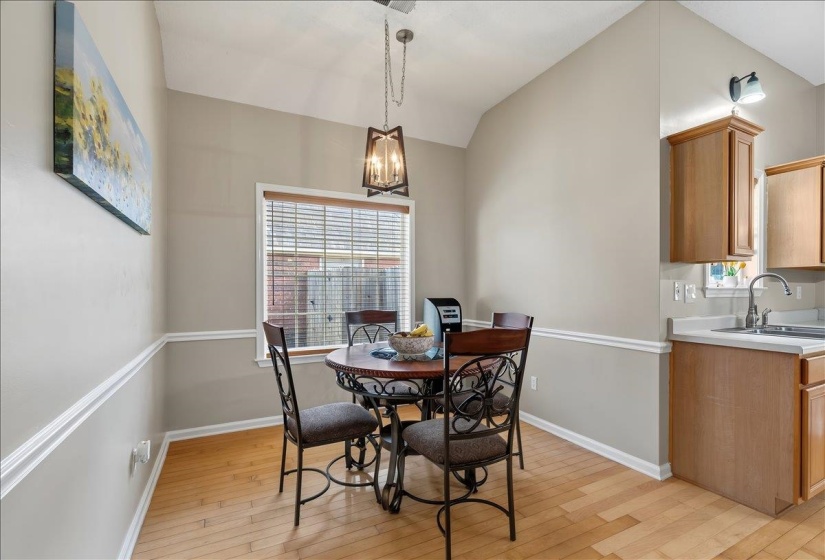 Dining area featuring a vaulted ceiling and wood-finish flooring