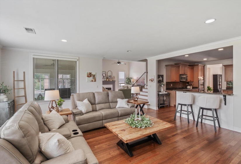Spacious living area with wood-finish flooring, recessed lighting, and a large window with blinds