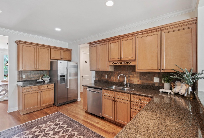 Kitchen featuring wood-finish cabinetry, granite-style countertops, mosaic tile backsplash, and stainless steel appliances