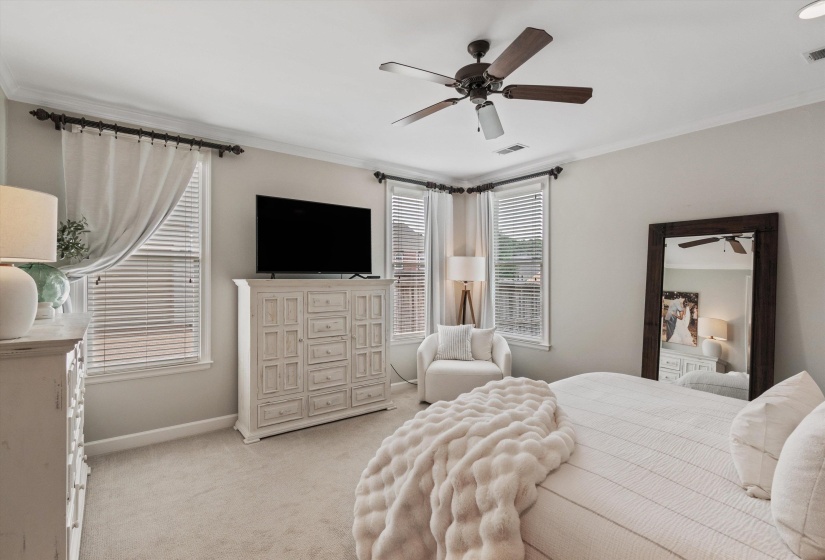 Carpeted room featuring multiple windows with blinds and curtains, a ceiling fan with integrated lighting, and crown molding