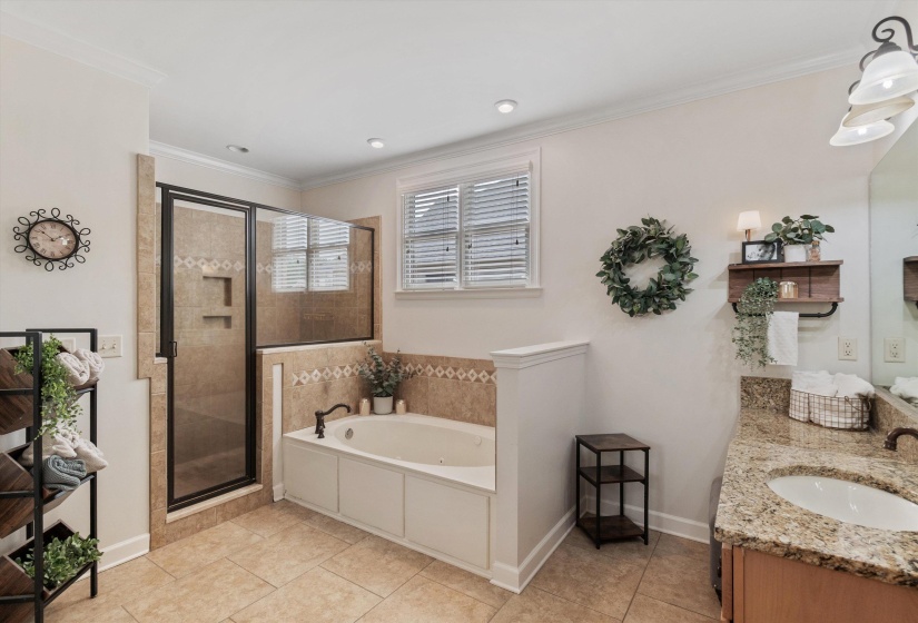 Bathroom featuring a built-in jetted tub, a tiled walk-in shower with a glass enclosure, a vanity with a granite-style countertop, and tile flooring