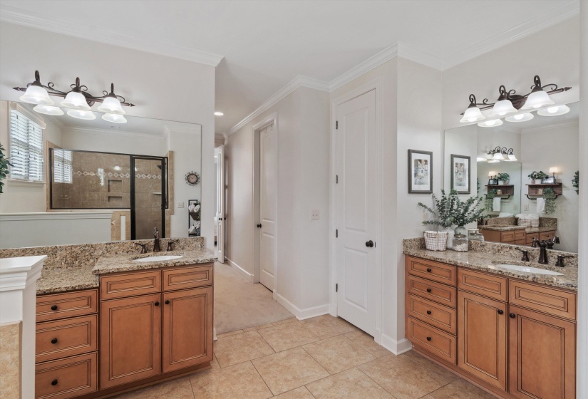 Double vanity with recessed sinks, granite countertops, and wood cabinetry
