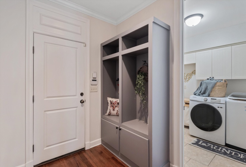 Entryway featuring wood-finish flooring and a built-in gray storage unit with open shelving and lower cabinetry