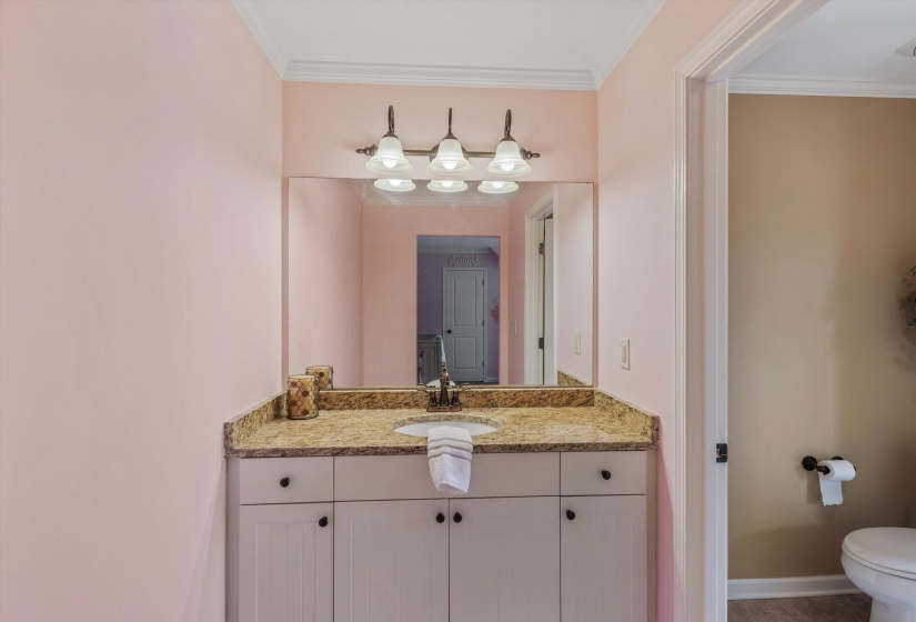 Bathroom vanity featuring a stone-finish countertop, undermount sink, and white cabinetry
