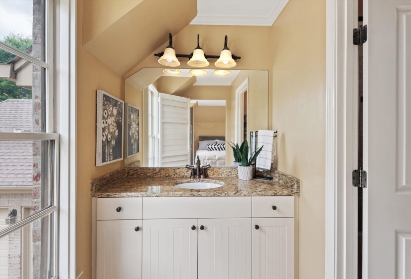 Vanity featuring a stone countertop with an undermount sink, white beadboard cabinetry, and a three-light fixture