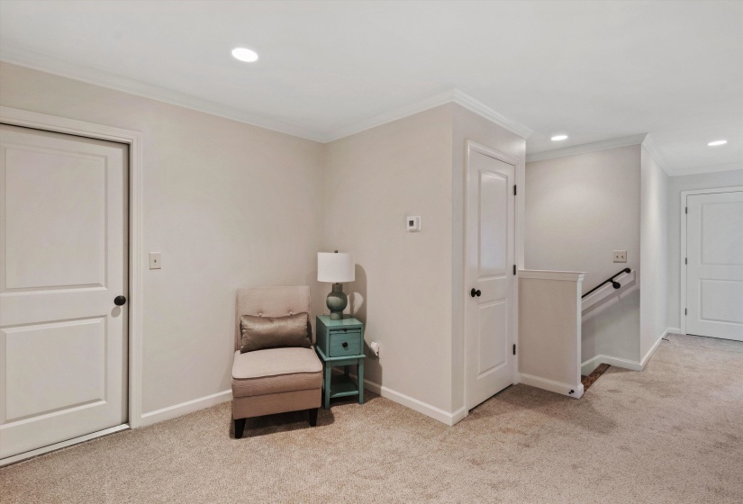 Carpeted hallway featuring white two-panel doors, recessed ceiling lighting, and crown molding