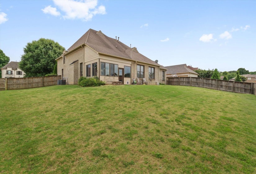 Expansive rear lawn featuring a wooden privacy fence