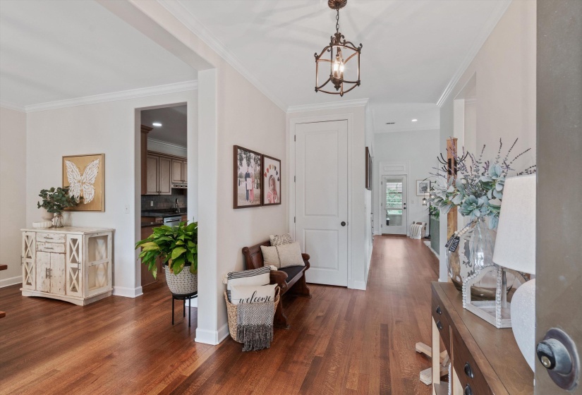 Bright entryway featuring wood-finish flooring, white trim, and a decorative overhead light fixture