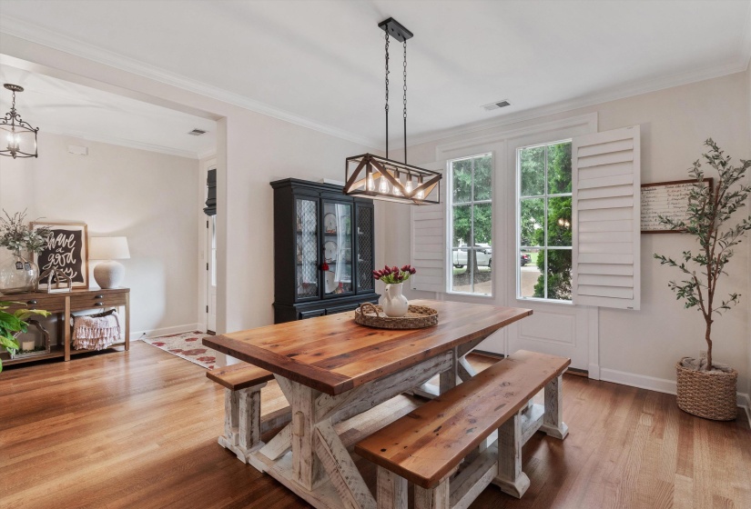 Dining area featuring wood-finish flooring, a linear chandelier, and a black display cabinet