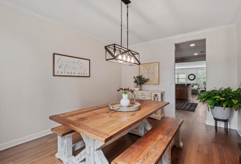 Dining area with wood-finish flooring, crown molding, and a rectangular open-frame chandelier