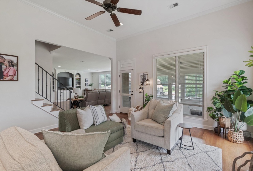High ceilings with crown molding, wood-finish flooring, and a ceiling fan create an inviting atmosphere