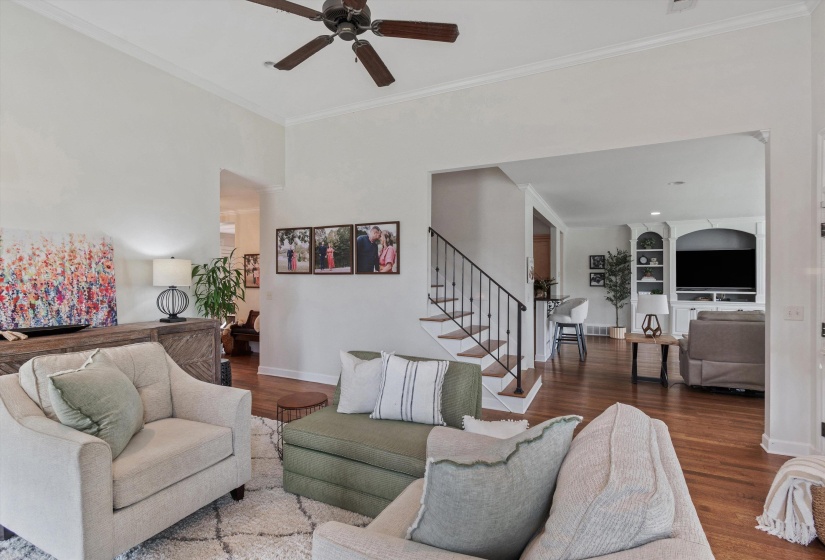Spacious living area featuring high ceilings with crown molding, wood-finish flooring, and a ceiling fan