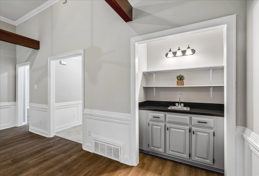 Built-in wet bar featuring gray cabinetry, a dark countertop, and a stainless steel sink with a chrome faucet