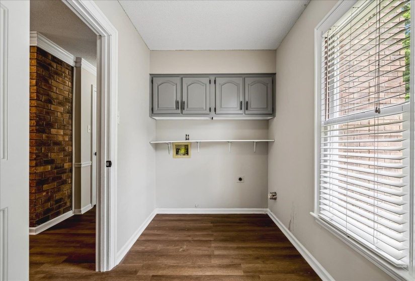 Dedicated utility room featuring wood-finish flooring, light gray wall paint, and a large window with blinds
