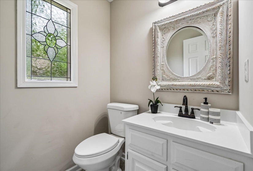 Bathroom featuring a white vanity with integrated sink, dark bronze-finish faucet, and an ornate framed mirror