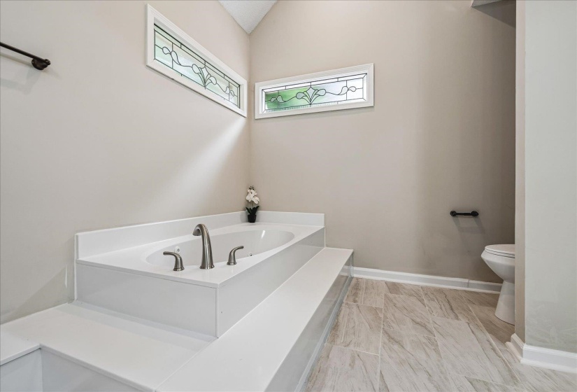 Built-in soaking tub with brushed nickel fixtures, accented by stained-glass transoms