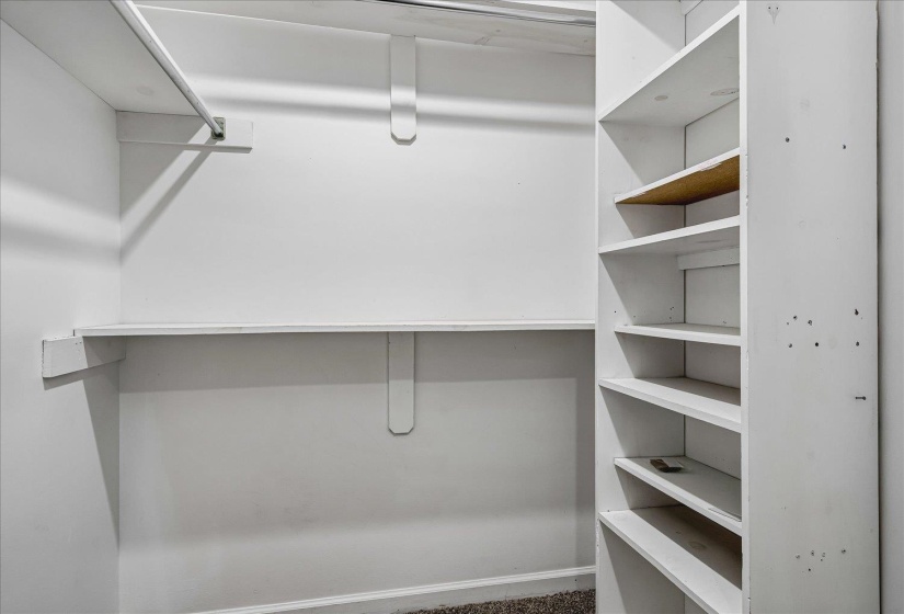 Walk-in closet featuring white painted walls and built-in shelving