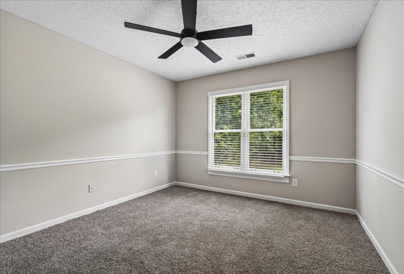 Neutral-toned room featuring a window with blinds, a ceiling fan, and grey carpet