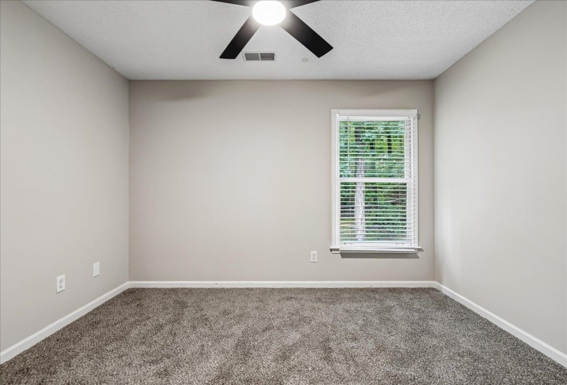 Spacious room featuring neutral paint, gray carpet, a single window with blinds, and a ceiling fan with light fixture