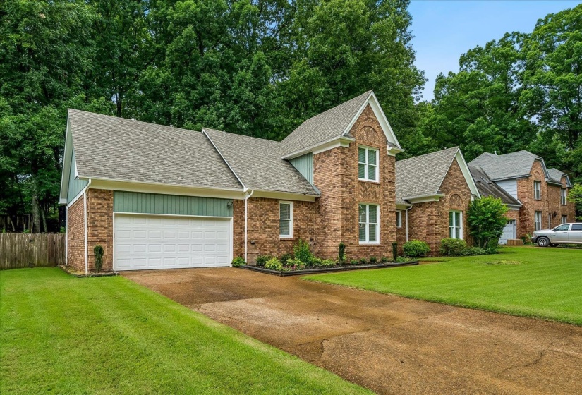 Brick exterior featuring multiple gables, an attached two-car garage, and mature landscaping