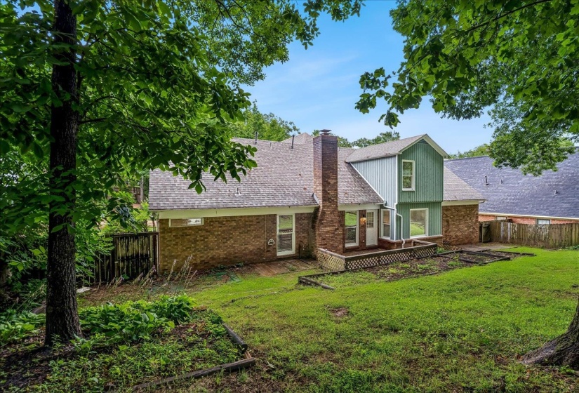 Brick and siding exterior featuring a multi-level roofline, a brick chimney, and a wooden deck