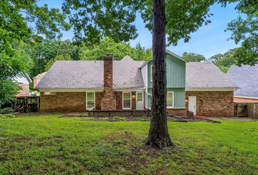 Expansive rear yard featuring a brick and siding exterior with a prominent brick chimney