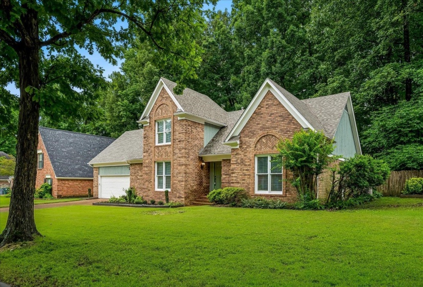 Traditional-style residence featuring a brick and siding exterior with gabled rooflines, an attached garage, and a lush green lawn