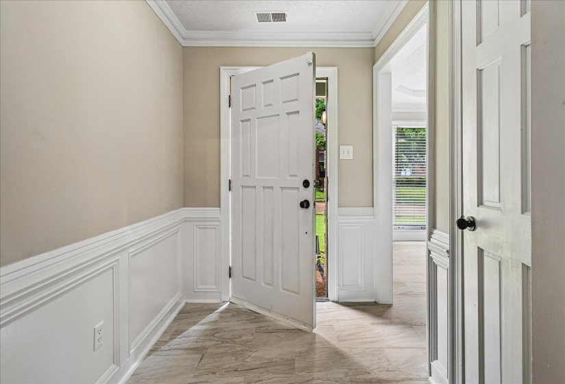 Entryway featuring neutral wall paint, white wainscoting, and a multi-panel door