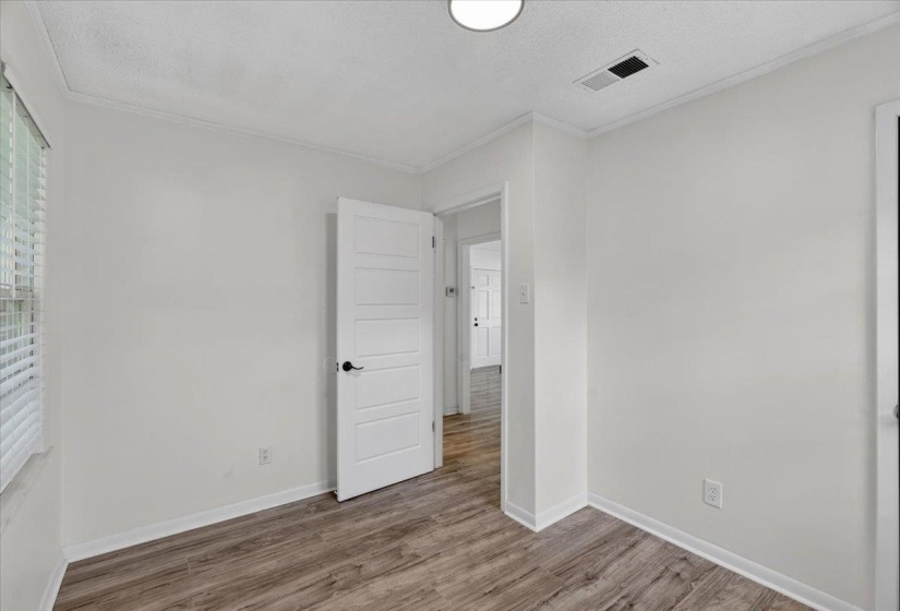 Bright room featuring wood-finish flooring, white walls, and a contemporary five-panel interior door