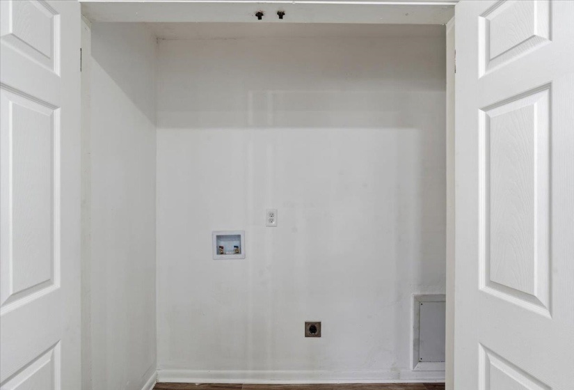Dedicated laundry area featuring white walls, wood-finish flooring, a washer hookup, and an electrical outlet