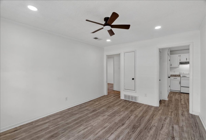Spacious room featuring wood-finish flooring, white walls, and recessed lighting