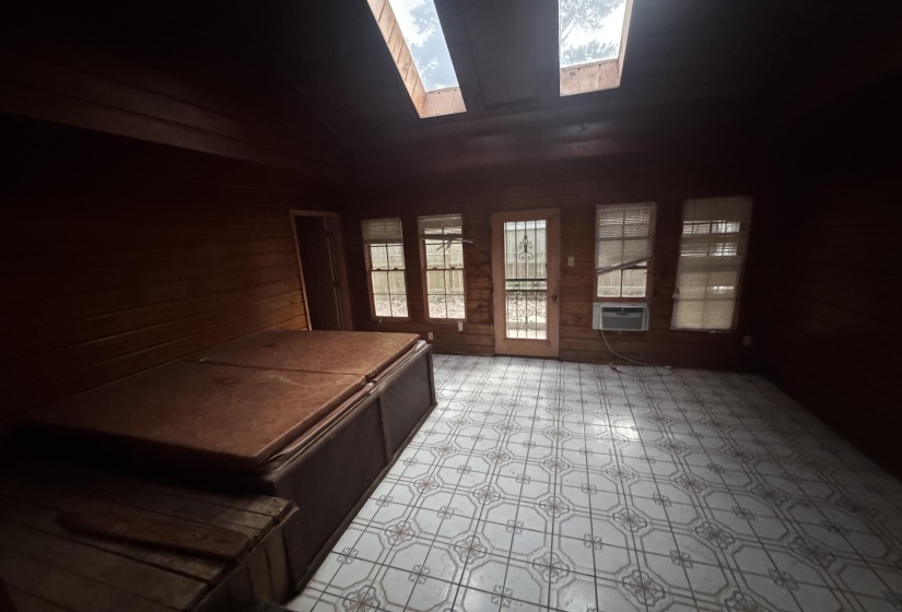 Interior space featuring plank wood walls, patterned tile flooring, and multiple windows