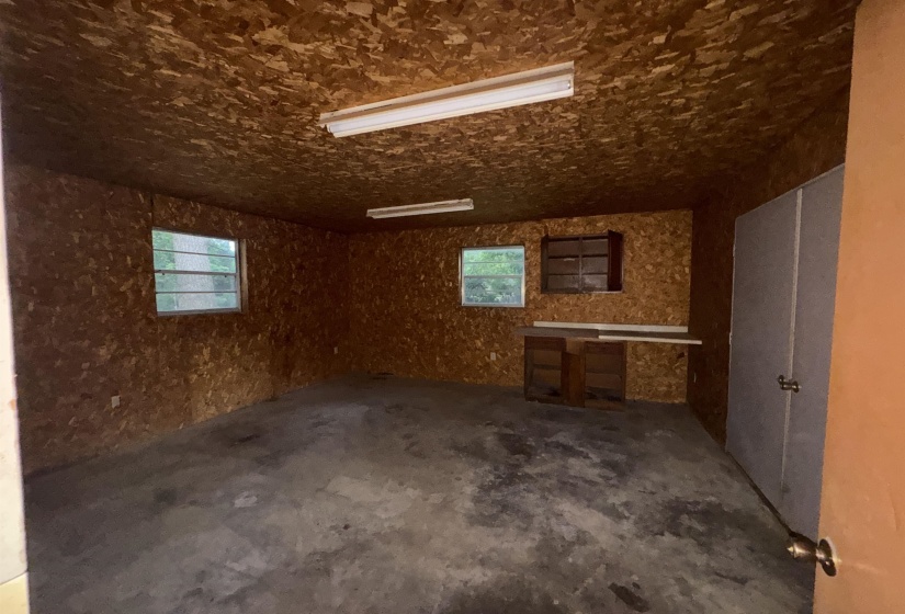 Spacious utility room featuring a concrete floor, two windows providing natural light, and two fluorescent ceiling light fixtures