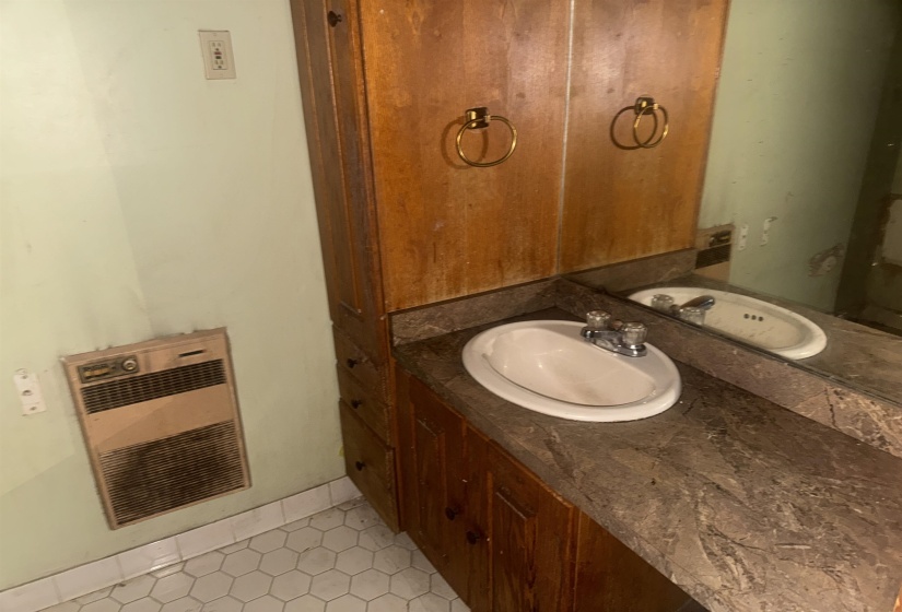 Vanity with integrated sink and chrome faucet, set against a full-width mirror