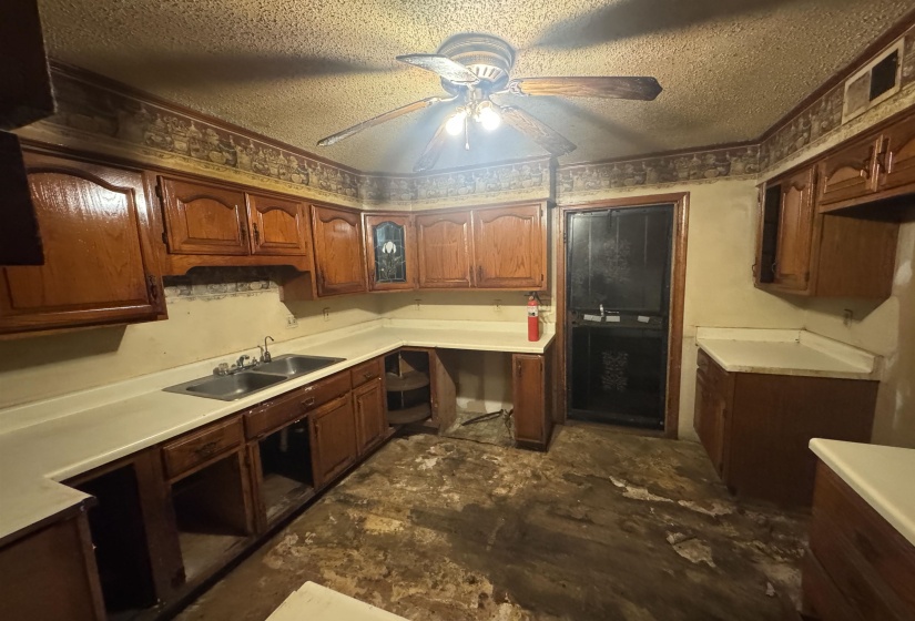 Kitchen featuring wood-finish cabinetry, light-toned countertops, and a double basin stainless steel sink