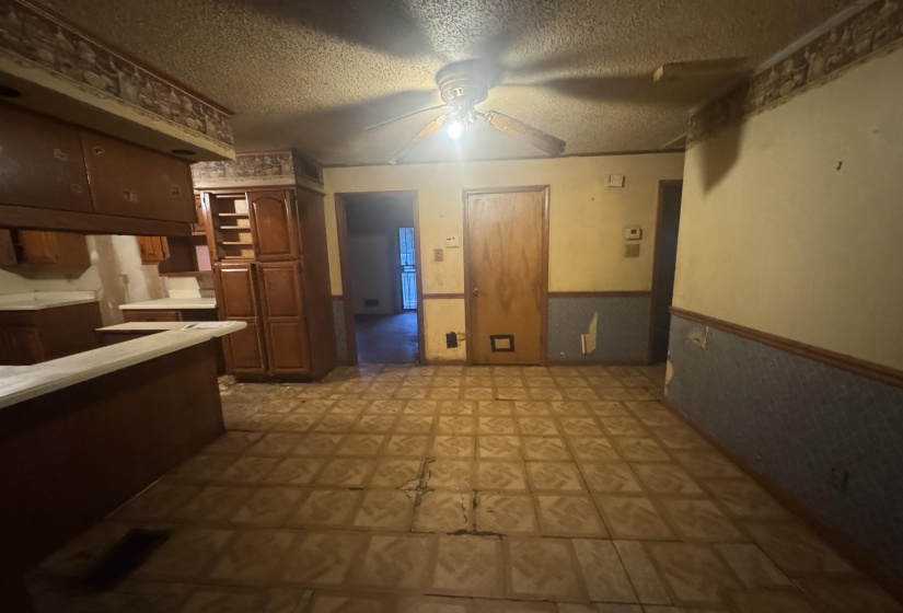 Kitchen area featuring dark wood-finish cabinetry, a built-in pantry, white countertops, and patterned floor tiling