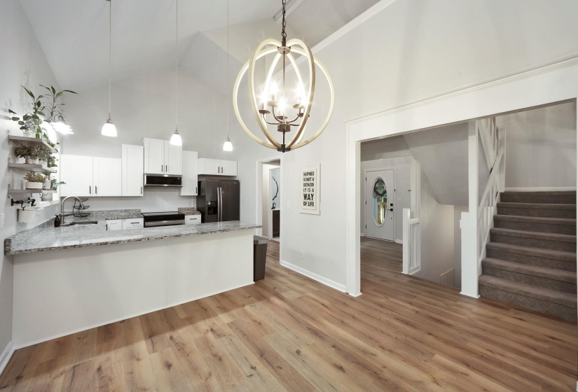 Open-concept kitchen and living area featuring vaulted ceilings and wood-finish flooring