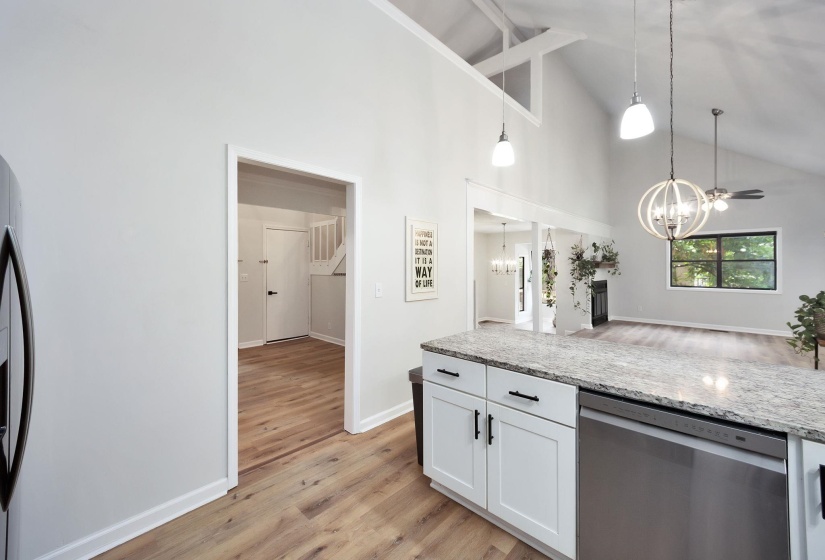 Kitchen island featuring a light-toned stone countertop, white shaker-style cabinetry with matte black hardware, and an integrated stainless steel dishwasher